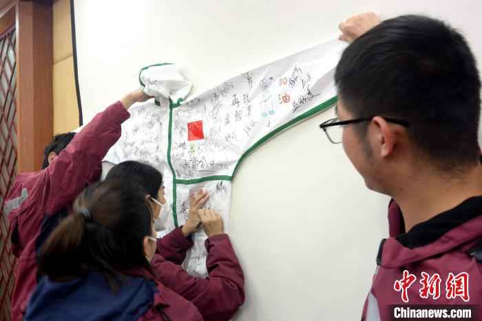 支援湖北医疗队员在防护服上签名、写祝福,留下纪念。 龚雯 摄  福建漳州首批驰援湖北医疗队凯旋:想念家乡味道